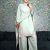 A woman modeling a pale green traditional Indian outfit with intricate pink and silver embroidery.